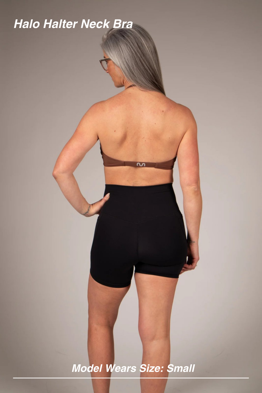 Mint Activewear Halo Halter Neck Bra in brown, full back view with black shorts showing the open-back halter design.