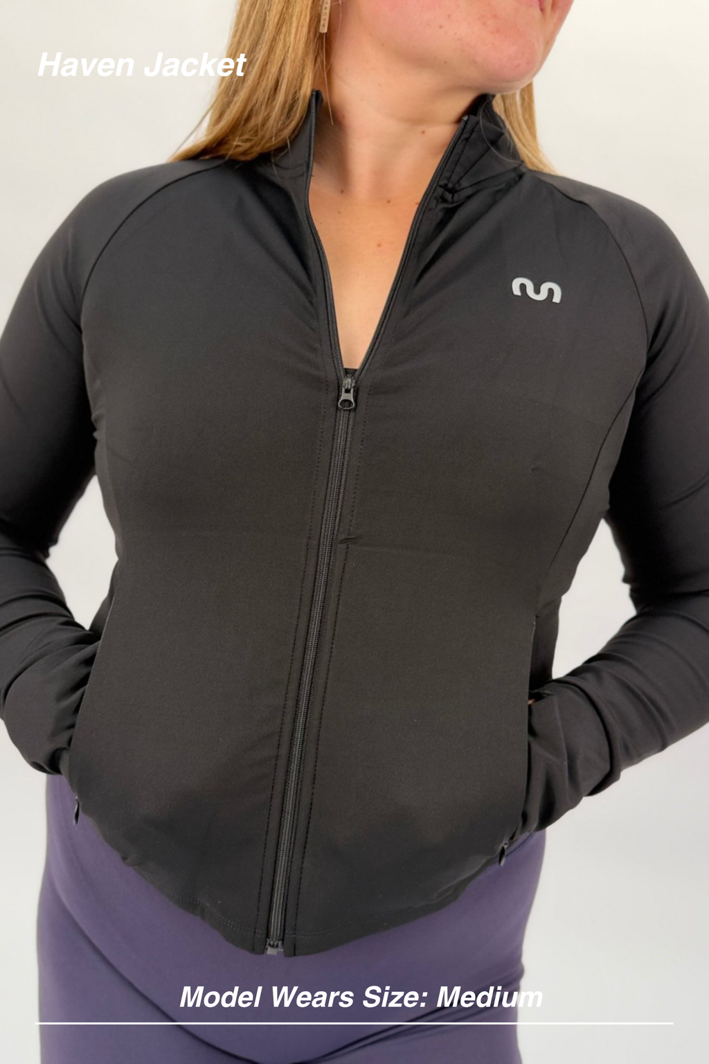 Mint Activewear Haven Jacket in black, close-up front detail of the full-length zip and silver M logo.