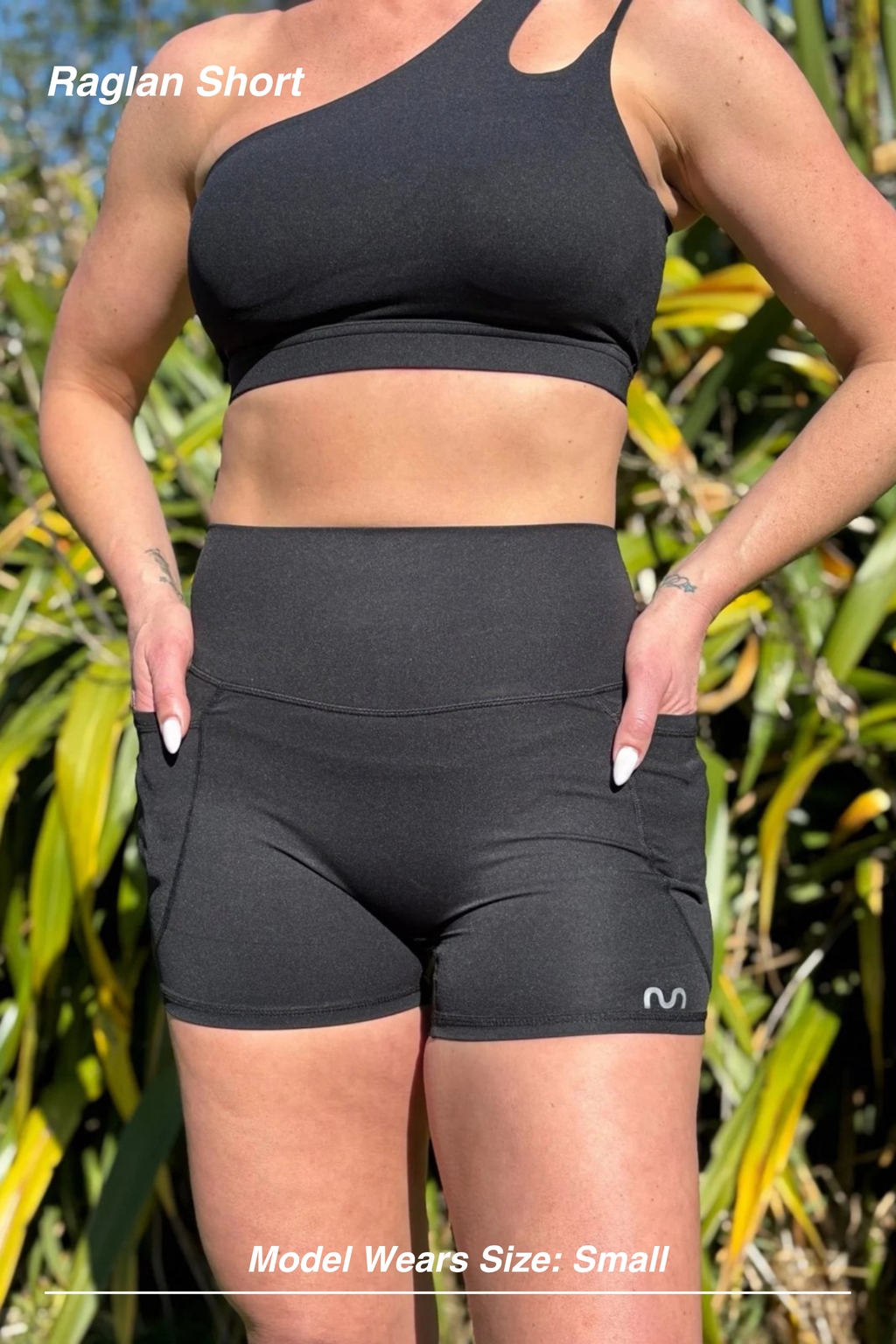 Mint Activewear Raglan Short in black, front view worn outdoors with a one-shoulder sports bra.