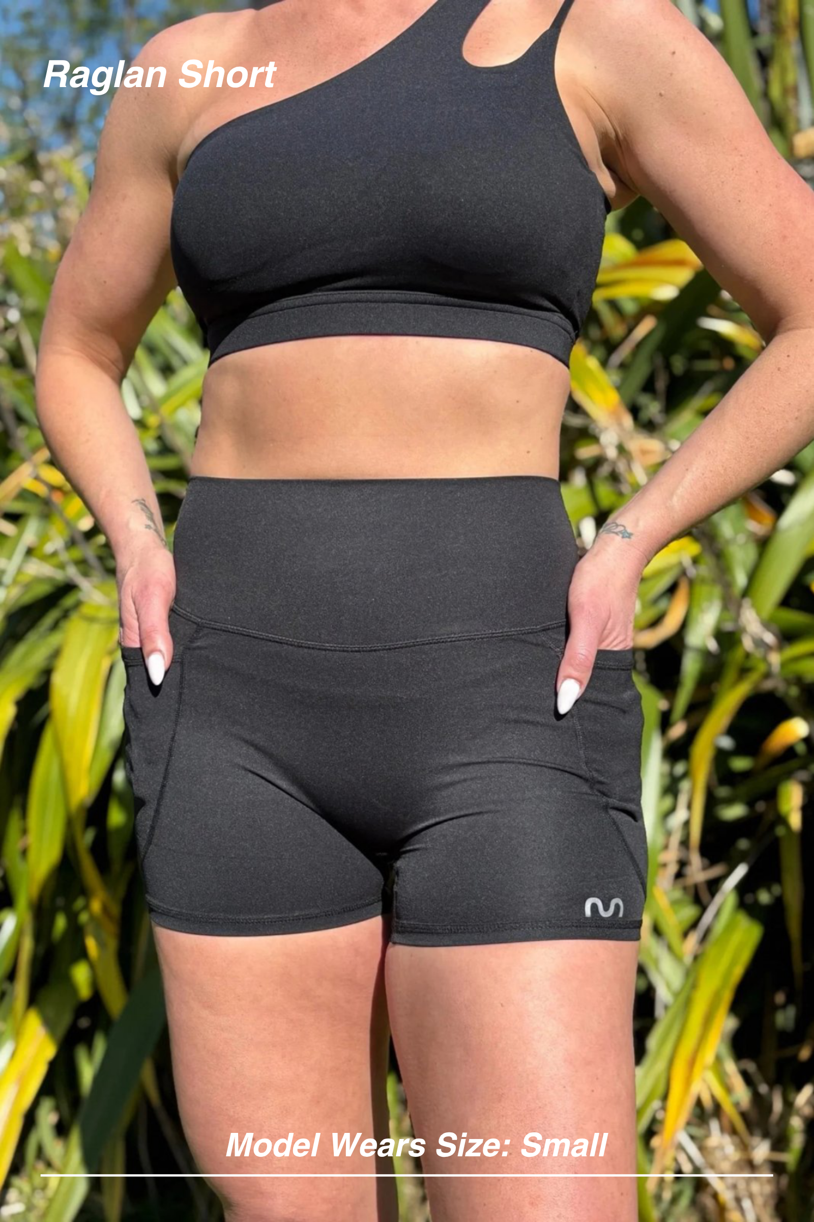 Mint Activewear Raglan Short in black, front view worn outdoors with a one-shoulder sports bra.