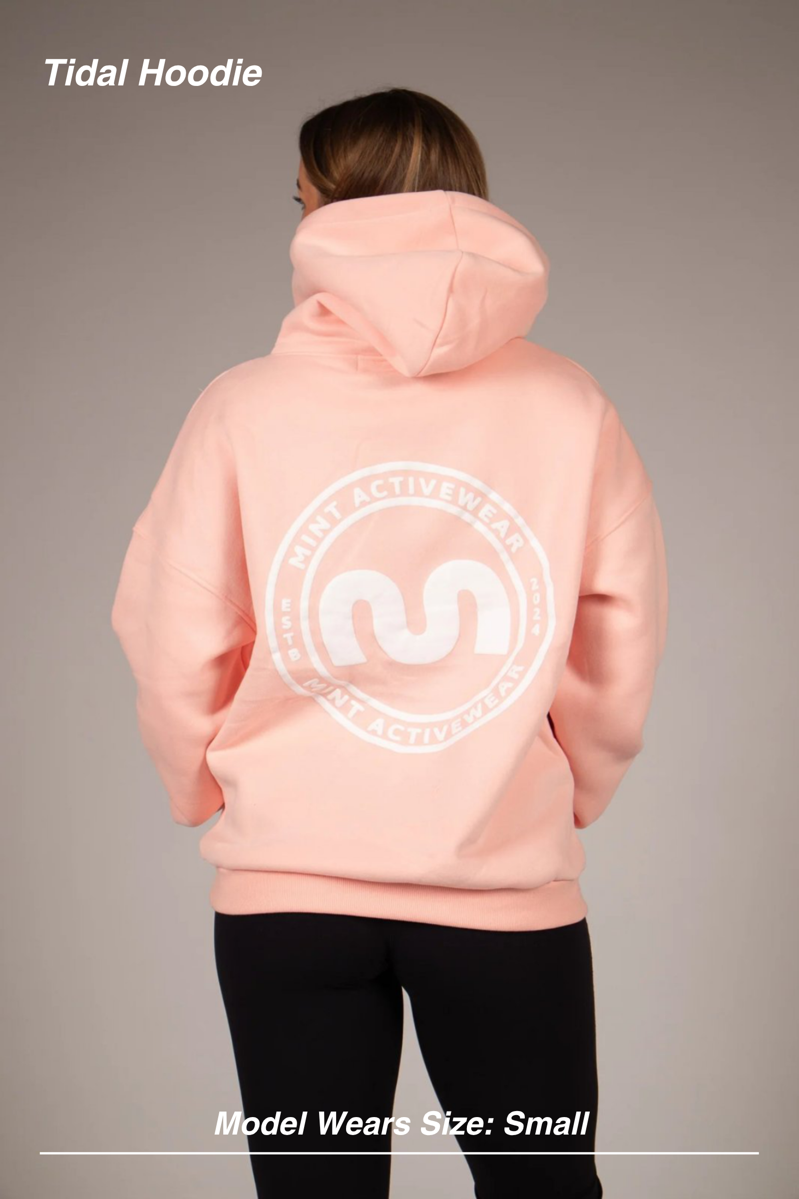 Mint Activewear Tidal Hoodie in peachy pink, back view with the white circular logo print and hands in pockets.
