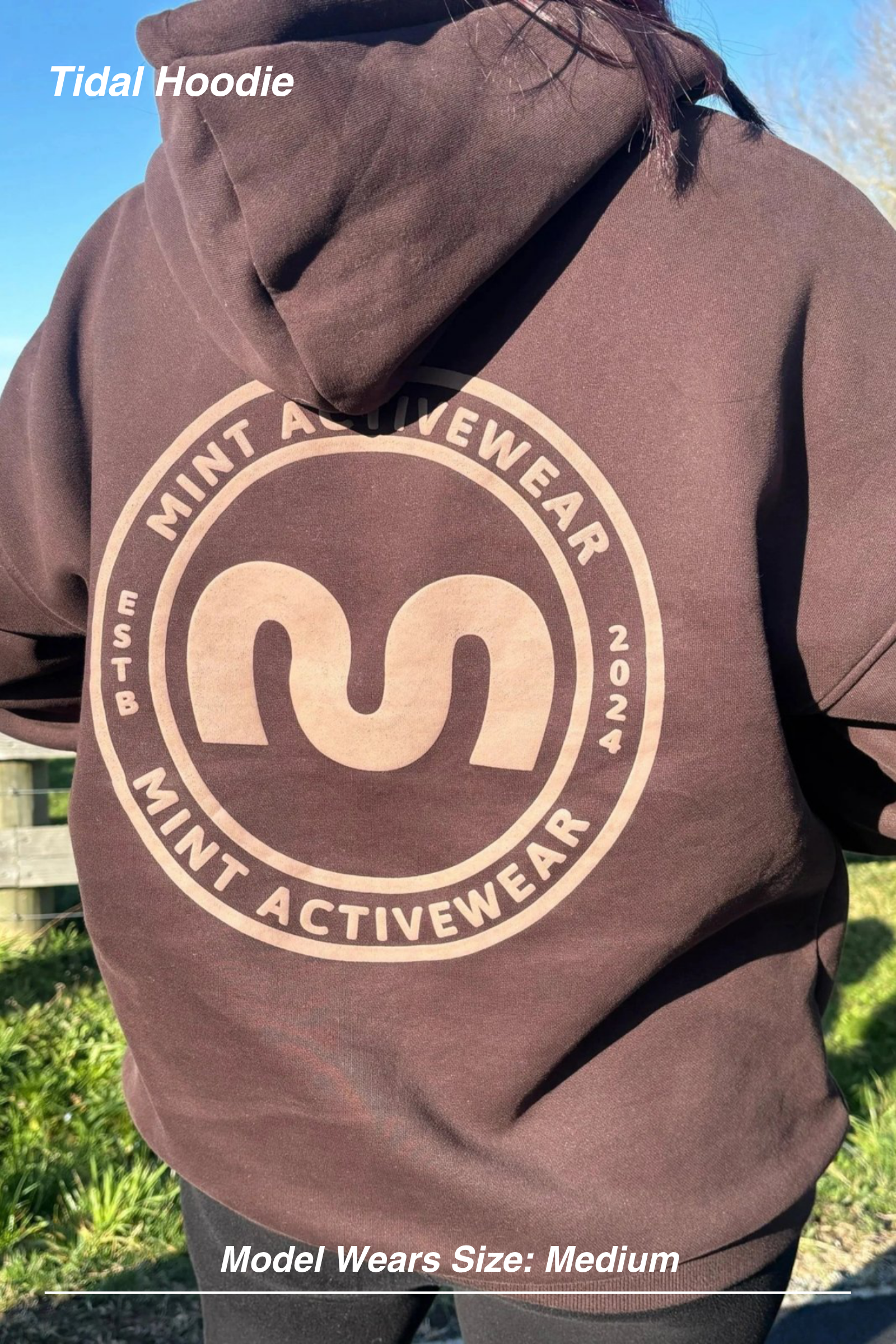 Mint Activewear Tidal Hoodie in chocolate, back view with the large tonal circular logo print outdoors.