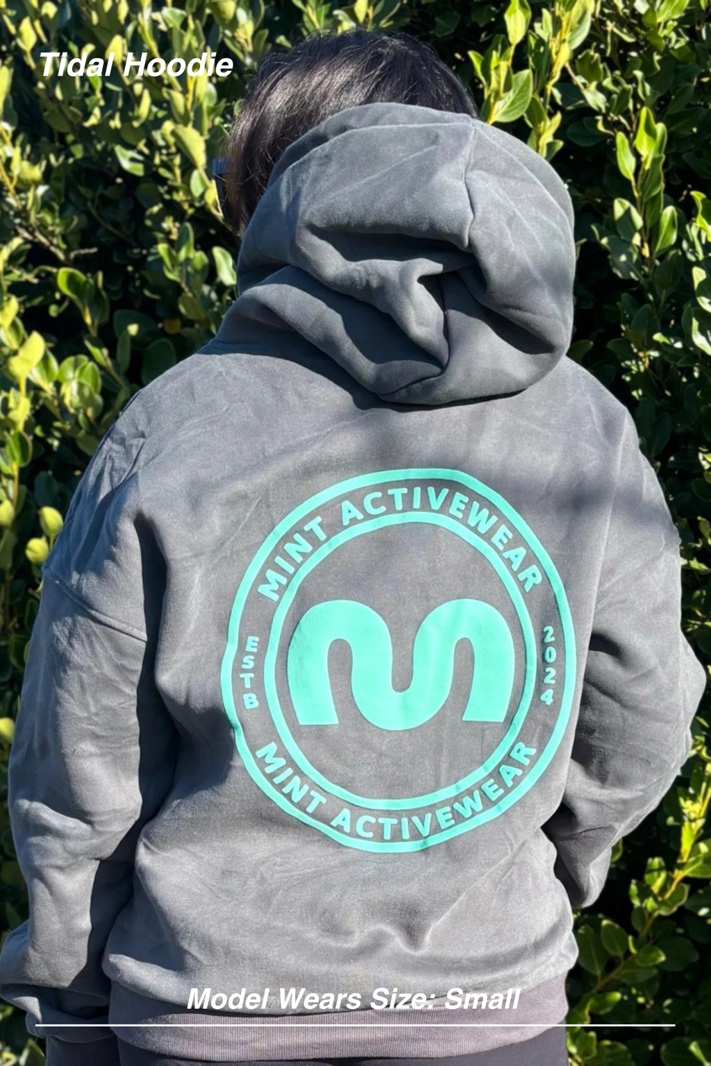 Mint Activewear Tidal Hoodie in slate, back view with a bright mint circular logo print, shot outdoors.