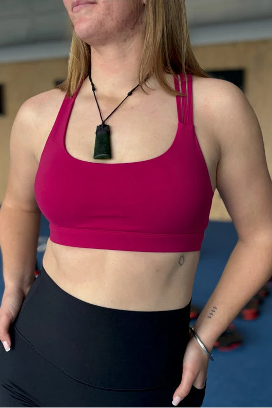 Person wearing a pink sports bra and black leggings indoors.